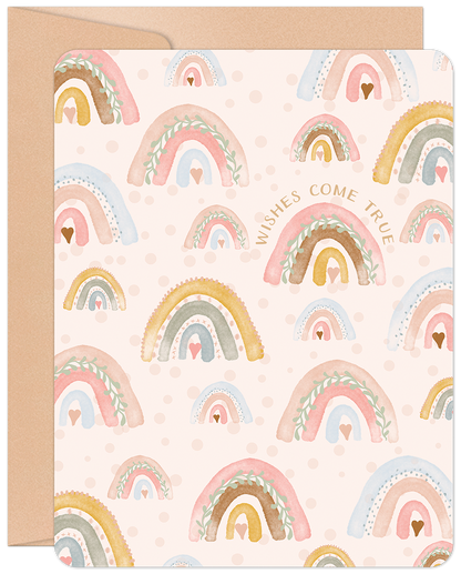 Cute new baby greeting card with watercolor rainbows, hearts, and "Wishes Come True" text, on a craft paper envelope.