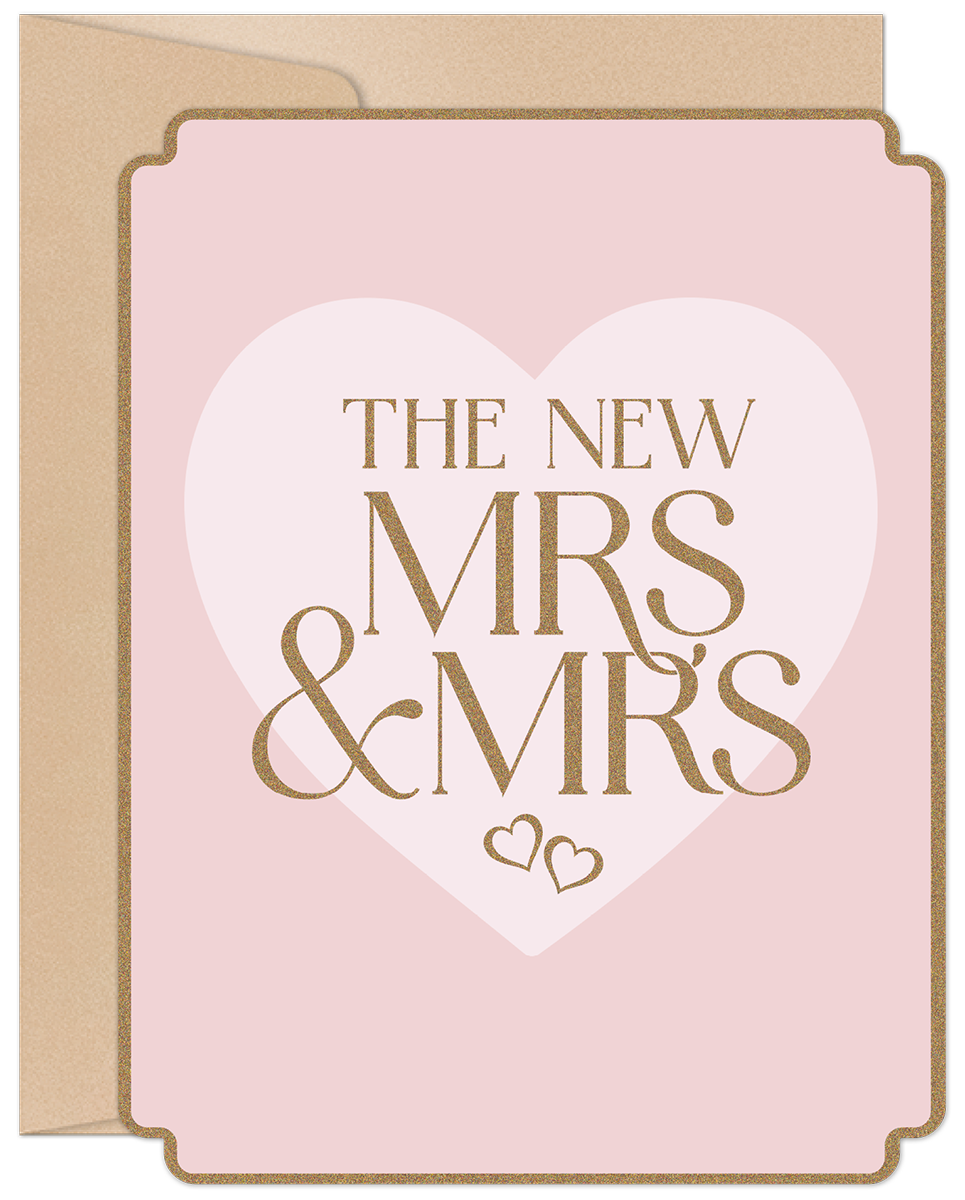 Front of a modern pink wedding greeting card for two brides, featuring gold glitter text 'THE NEW MRS & MRS' within a large white heart, bordered by a subtle gold trim, with a kraft envelope visible behind.