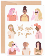 Front of 'All Eyes On You' greeting card for a woman's new job, featuring diverse women wearing glasses and sunglasses with an encouraging message for a friend or coworker.