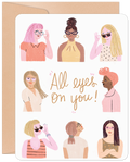 Front of 'All Eyes On You' greeting card for a woman's new job, featuring diverse women wearing glasses and sunglasses with an encouraging message for a friend or coworker.