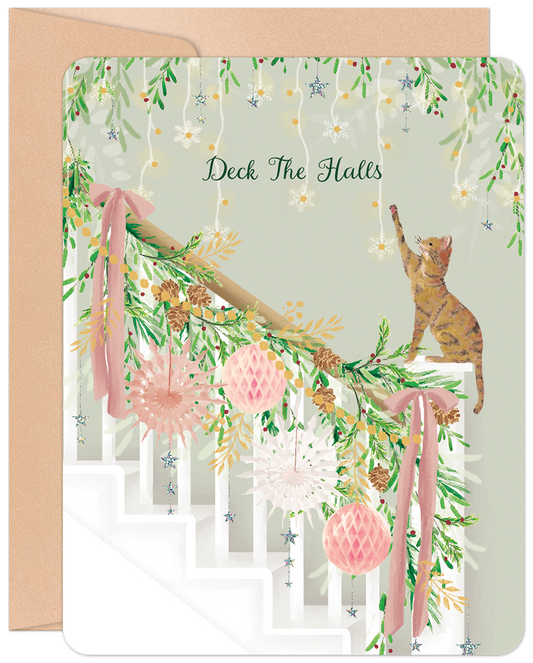 Front of 'Deck The Halls' Christmas card with a cute cat decorating a festive staircase adorned with pink ribbons and holiday lights.