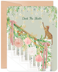 Cute cat decorating a festive green and pink garland on a white staircase, with 'Deck The Halls' text. Ideal holiday greeting card for friends and family.