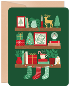 Front of a festive green holiday greeting card featuring three decorated shelves with charming illustrations of gifts, mini Christmas trees, a reindeer, snowman globe, candles, mugs, and stockings, perfect for spreading cheer.