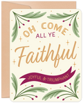 Front of a religious holiday greeting card featuring the text 'Oh Come All Ye Faithful' in gold and cream, surrounded by festive green branches with red berries on a light cream background, accompanied by a kraft paper envelope.