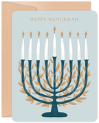 Elegant Hanukkah greeting card front featuring a teal and gold leaf menorah with nine lit candles, 'HAPPY HANUKKAH' text, and a matching envelope on a light blue background.