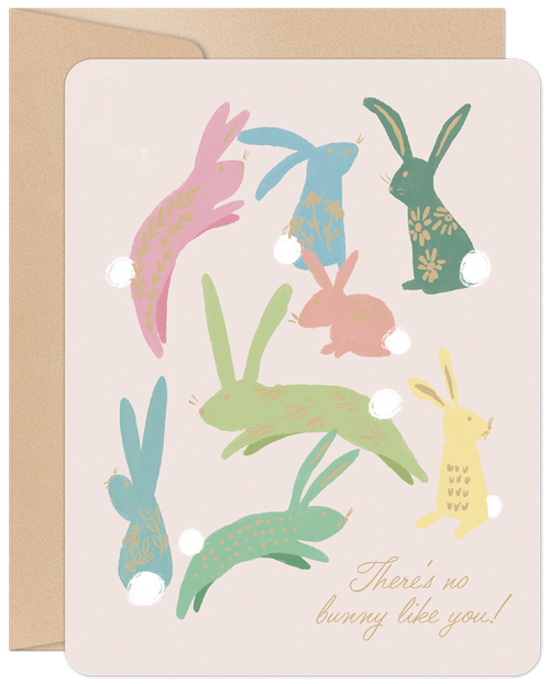 A cute greeting card with a light pink background featuring multiple stylized pastel bunnies in various shades of pink, blue, green, and yellow, each with unique decorative patterns and fluffy white tails. The bottom right corner has gold script text that reads 'There's no bunny like you!'. A brown kraft envelope is partially visible on the left side. Ideal for sending cheerful spring or celebration wishes.
