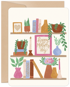 Illustrated Mother's Day greeting card featuring a charming bookshelf with potted plants, colorful books (Recipes, Poetry, Gardening), and a framed message 'Happy Mother's Day' in elegant script. Ideal for mom, wife, or grandma.