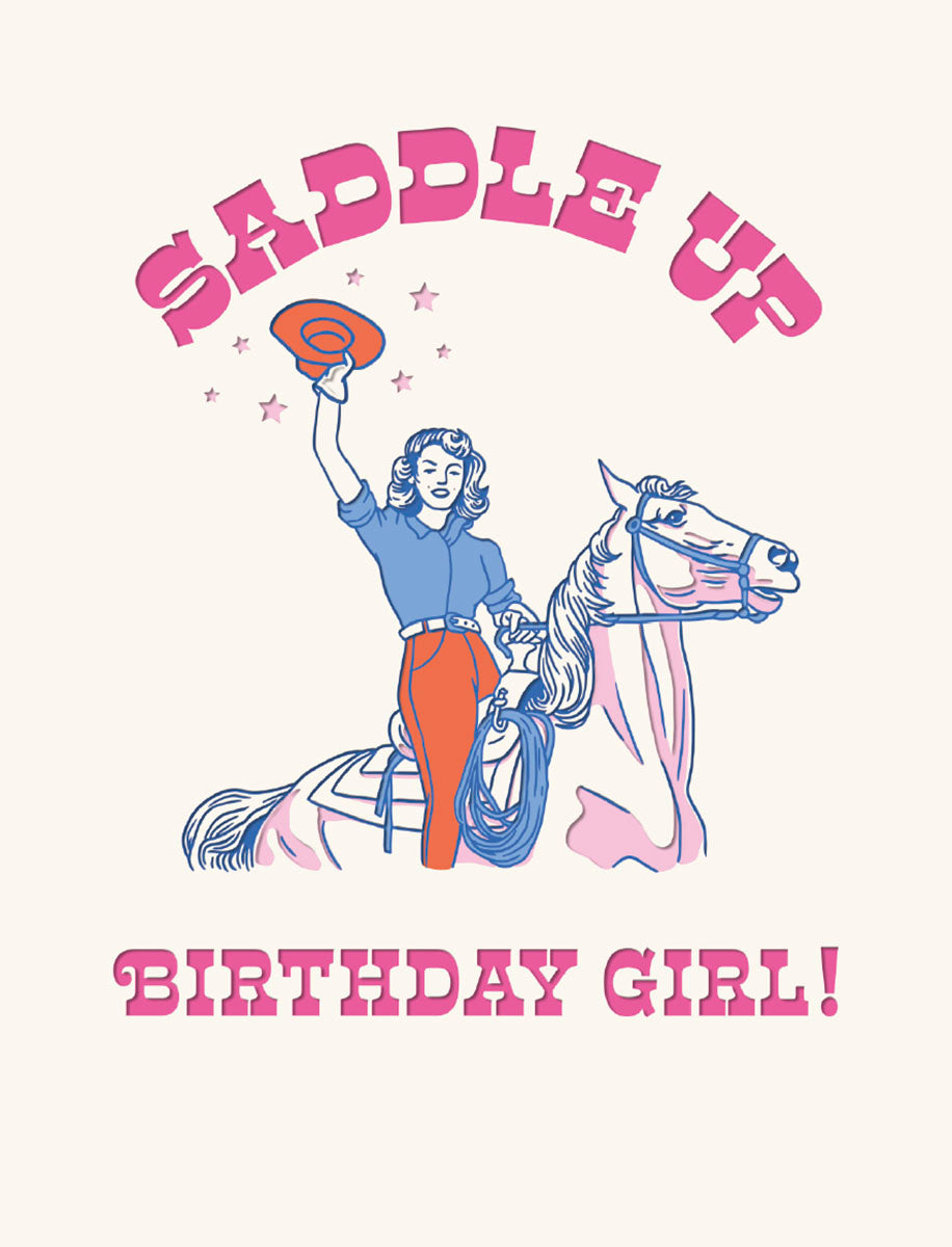 Front of a retro-inspired pink and blue greeting card featuring a cheerful cowgirl in red pants and blue shirt, hat raised, riding a pale pink horse. Bold pink text reads 'SADDLE UP' and 'BIRTHDAY GIRL!' surrounded by small stars.