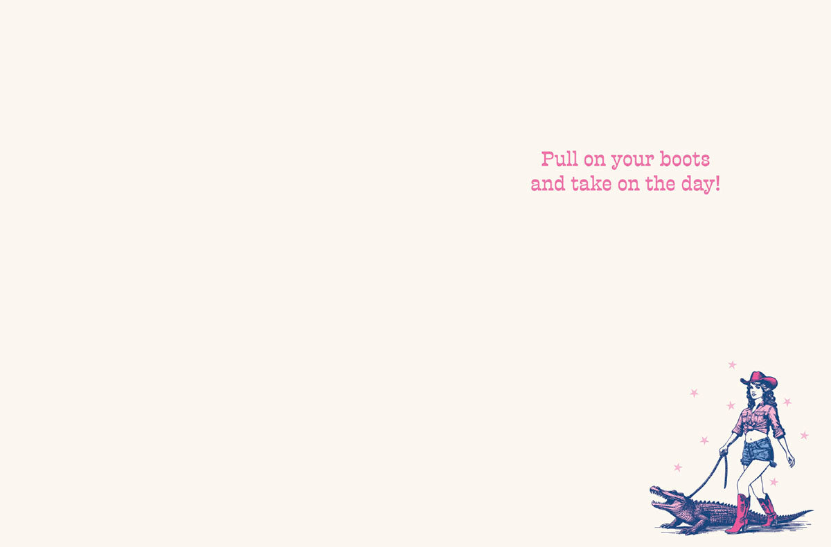 Inside of a greeting card with a small illustration of a cowgirl walking an alligator, and text 'Pull on your boots and take on the day!' on a light background.