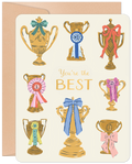Front of a friendship greeting card with multiple gold trophies adorned with colorful ribbons and bows, proclaiming 'You're the BEST' on a cream background, celebrating a top friend.