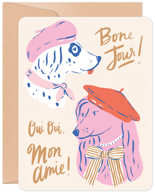 Front of a cute friendship greeting card featuring a pink poodle and a white spotted dog wearing berets, with French-themed text 'Bone Jour!' and 'Oui Oui, Mon Amie!' on a cream background, with a kraft envelope visible.