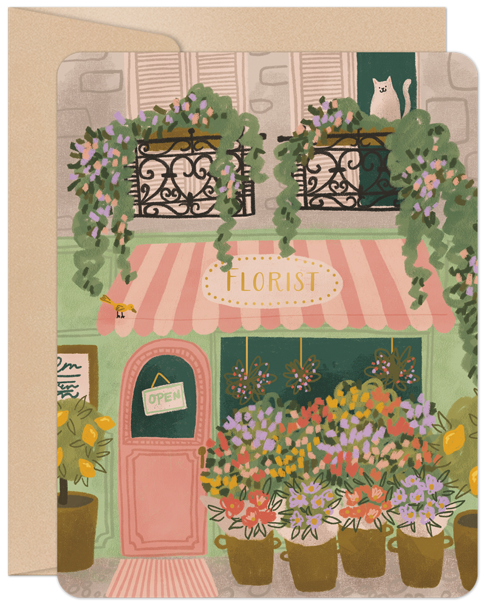 Front of an encouraging get well card featuring a charming, hand-drawn illustration of a Parisian florist shop with a pink awning, potted lemon trees, vibrant flowers, and a white cat peeking from an upstairs window. An 'OPEN' sign hangs on the door.