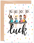 Front of an encouraging greeting card featuring four diverse female cheerleaders in black and white striped outfits holding 'GOOD' flags and colorful pom-poms, surrounded by confetti, with 'luck' in script below. Perfect for friends embarking on new journeys.