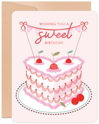 Romantic birthday greeting card with a heart-shaped pink cake, cherries, and 'Wishing you a sweet Birthday' banner on a light background with kraft envelope.