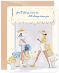 Front of a heartfelt greeting card for her friend. Features an elegant illustration of two women in stylish wide-brimmed hats and summer outfits, surrounded by blue and yellow flowers. Text reads: 'You'll always have me. I'll always have you.'