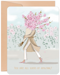 Vibrant uplifting greeting card for her featuring a stylish figure with a head of pink cherry blossoms, wearing a trench coat, walking through a garden with the uplifting message 'YOU ARE ALL SORTS OF AMAZING!' perfect for a friend.