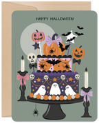 Cute Halloween greeting card featuring a multi-tiered spooky cake decorated with smiling pumpkins, friendly ghosts, bats, spiders, skulls, and candles, set against a full moon on a teal background.