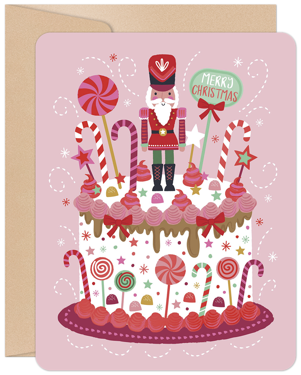 Pink festive greeting card featuring a decorated white cake with a nutcracker, candy canes, lollipops, stars, and 'Merry Christmas' text.