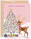 Whimsical pink festive greeting card featuring a reindeer wearing a striped scarf, a gold-starred decorated fir tree, and colorful presents under falling snow, with 'MERRY CHRISTMAS' text.
