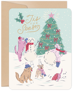 Cute illustration of dogs playing in a snowy winter scene around a decorated evergreen, building a snowman, perfect for festive greetings.