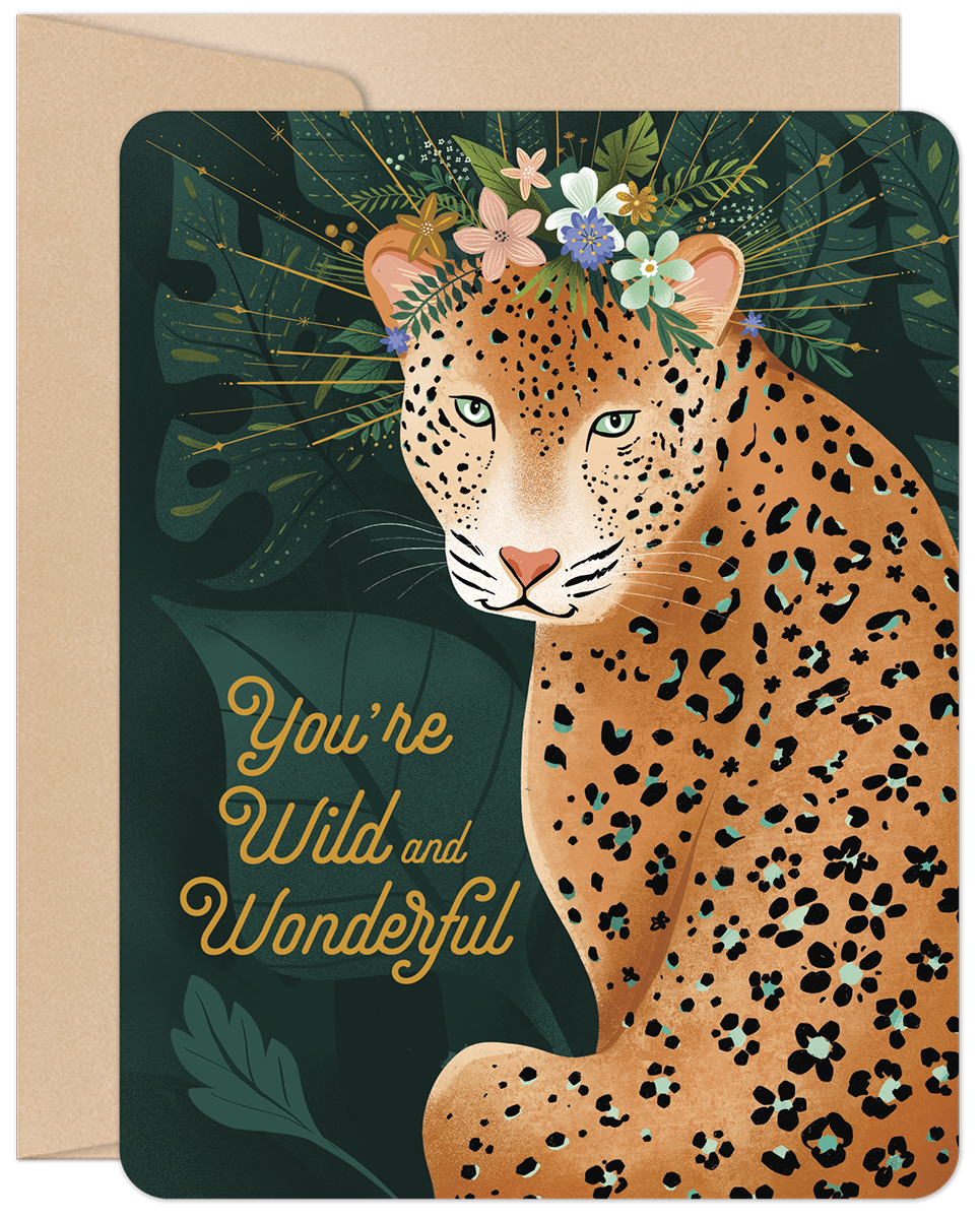 Front of a greeting card featuring an elegant leopard with teal eyes, adorned with a vibrant flower crown, surrounded by lush jungle foliage. The card displays the warm message 'You're Wild and Wonderful' in stylish script, perfect for a special anyone.