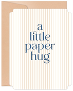 Elegant white greeting card with vertical gold pinstripes and navy text 'a little paper hug', peeking from a kraft brown envelope. Perfect for sending love and comfort.